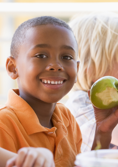 Young Black Boy Smiles Holding a Green Apple