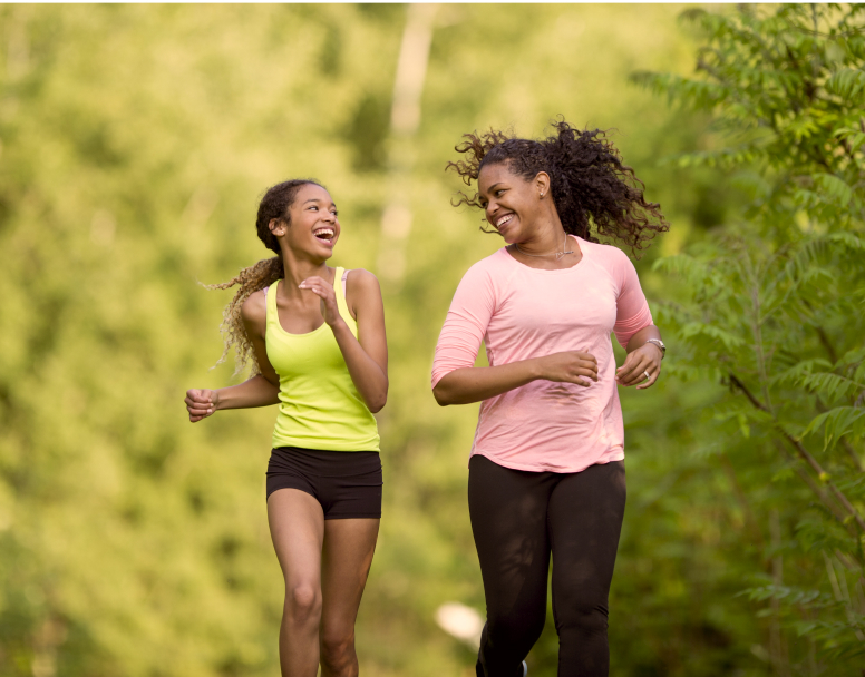 Two Young Women Smiling While Running Together Outside